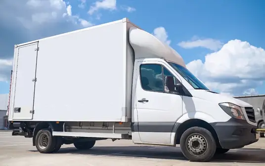 White delivery truck parked in an open lot ready for dispatch